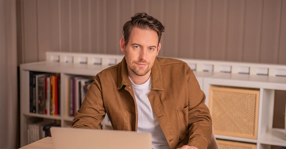 Bence Székely, co-founder of Frem Digital, sitting at his desk and smiling at the camera