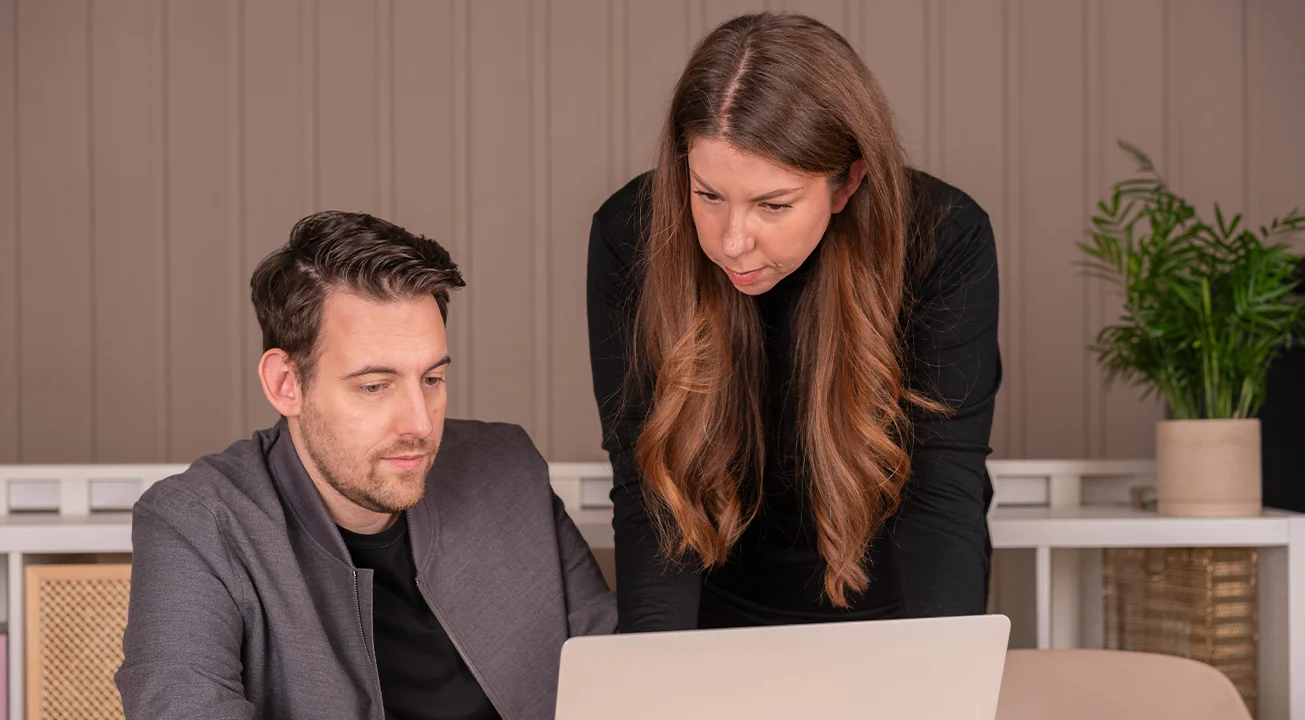 Bence Székely and Orsi Imreh working on a marketing project on a laptop in a modern office setting.