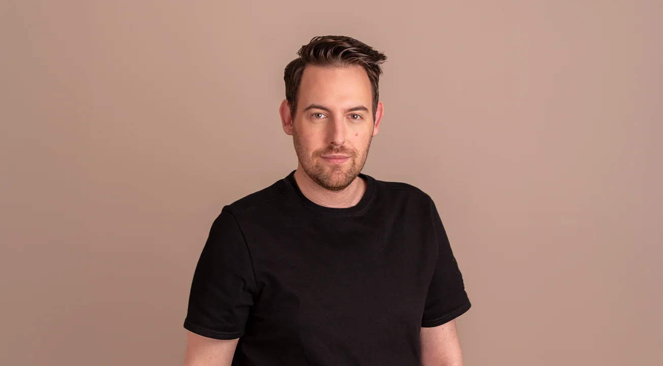 Bence Székely, the digital marketing strategist of Frem Digital stands against a plain beige background.