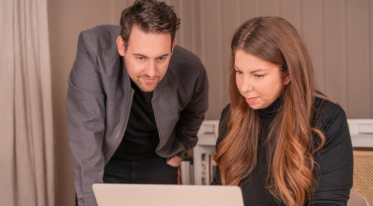 Bence Székely and Orsi Imreh are looking at a laptop screen together indoors.