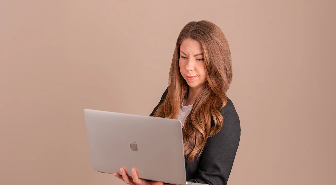 Orsi Imreh, a Google Ads Consultant, looks at an open laptop against a plain beige background.