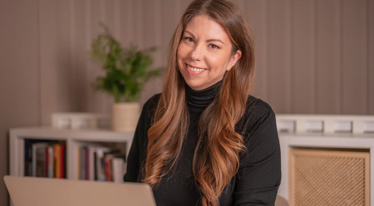 Orsi Imreh, Co-Founder and Performance Lead of Frem Digital, sits at a table and smiles at the camera.