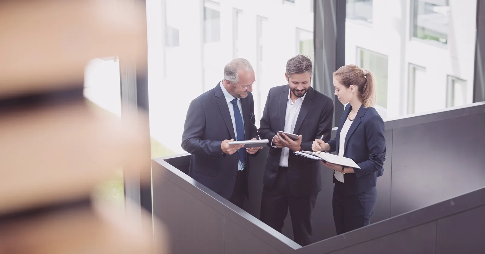 Business team in suits reviewing notes and tablets, symbolizing our corporate finance Facebook page management case study.